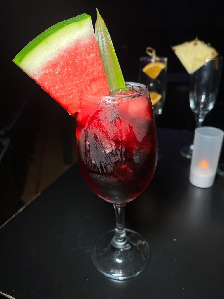 A refreshing watermelon sangria in a wine glass, garnished with a watermelon wedge.